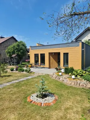 a yellow house with a tree in a yard at Sipis House in Šiauliai