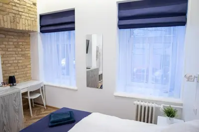 a bedroom with a bed and a desk and windows at HOT SPOT Vilnius Apartments! in Vilnius
