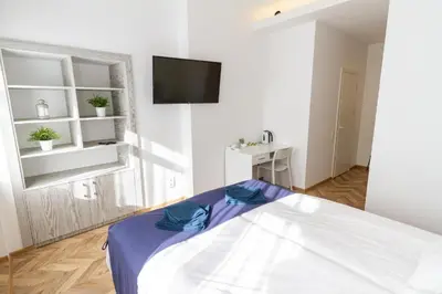 a white bedroom with a bed and a flat screen tv at HOT SPOT Vilnius Apartments! in Vilnius