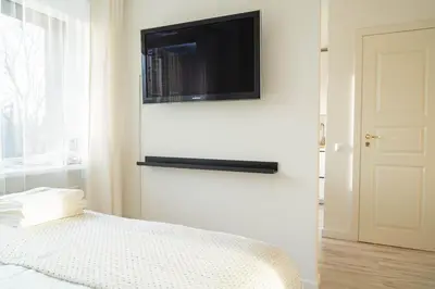 a bedroom with a bed with a television on the wall at Čia gera studio in Anykščiai