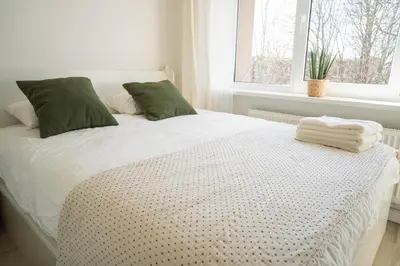 a white bed with green pillows and a window at Čia gera studio in Anykščiai