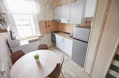 a small kitchen with a table and a white refrigerator at Kauko Laiptu Apartment in Kaunas