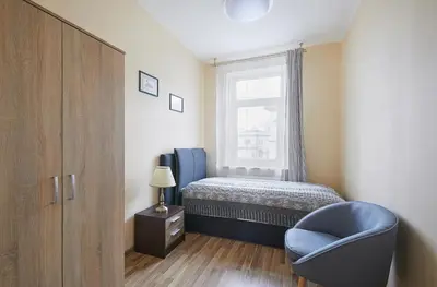 a bedroom with a bed and a blue chair at Kauko Laiptu Apartment in Kaunas