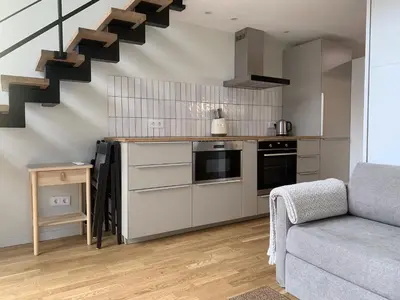 a kitchen with a couch and stairs in a room at Vilnius Cozy Loft in Vilnius