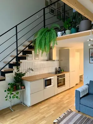 a living room with a kitchen and a staircase at Vilnius Cozy Loft in Vilnius