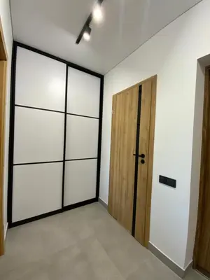 a room with white walls and a wooden door at Alėjos Apartmentai Comfort in Druskininkai