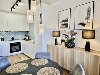 a kitchen and dining room with a table and chairs at Alėjos Apartmentai Comfort in Druskininkai
