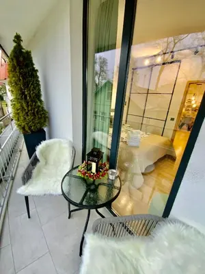 a glass table and chairs on a balcony at Alėjos Apartmentai Comfort in Druskininkai