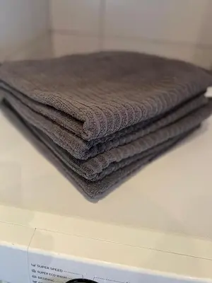a stack of brown towels sitting on top of a washing machine at Vilniaus 96 apartments in Ukmergė