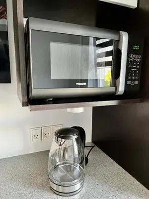 a microwave oven on a kitchen counter with a glass pitcher at Vilniaus 96 apartments in Ukmergė