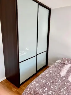 a bedroom with a bed and a large glass closet at Vilniaus 96 apartments in Ukmergė