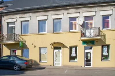 a car parked in front of a yellow building at Old Town apartments/Senamiesčio apartamentai in Ukmergė