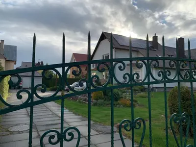 a green iron fence in front of a house at Green house Ramuciai in Ramučiai