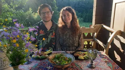 a man and a woman sitting at a table with food at Amatų kalnelis in Anykščiai