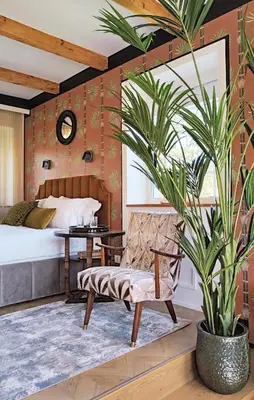 a bedroom with a bed and a chair and a plant at Suite with private bathroom at three bedroom interwar Villa Grabyte with daily spaces to share by pine forest on the bank of the river- 8min by car from old town in Kaunas