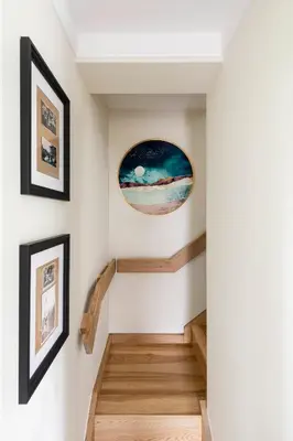 a stairway with two pictures on the wall and a painting at Suite with private bathroom at three bedroom interwar Villa Grabyte with daily spaces to share by pine forest on the bank of the river- 8min by car from old town in Kaunas