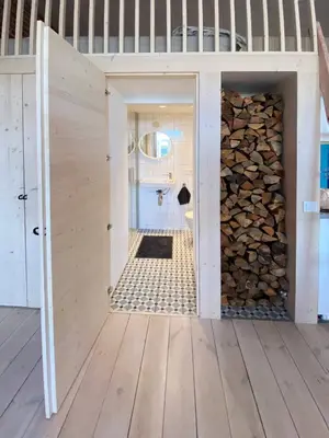 a tiny house with a bathroom and a pile of fire wood at Traukinių namai #2 in Švenčionėliai