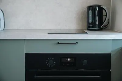 a microwave oven with a coffee pot on a counter at Grey Green Studio Apartment in Birštonas