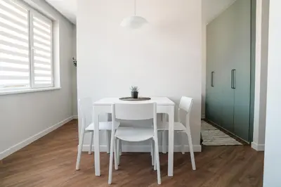 a white dining room with a white table and chairs at Grey Green Studio Apartment in Birštonas