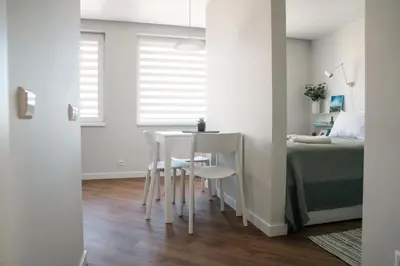 a white room with a bed and a table and chairs at Grey Green Studio Apartment in Birštonas