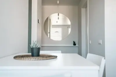 a dining room with a white table and a mirror at Grey Green Studio Apartment in Birštonas