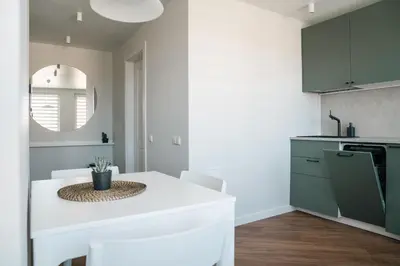 a kitchen with a white counter and a white table at Grey Green Studio Apartment in Birštonas