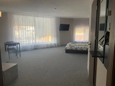 a bedroom with a bed and a table and windows at Hotel Marijampole in Marijampolė