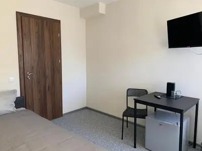 a bedroom with a bed and a desk with a television at Hotel Marijampole in Marijampolė