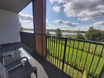 a balcony with a view of a field and water at Gilužio Rivjera in Vilnius