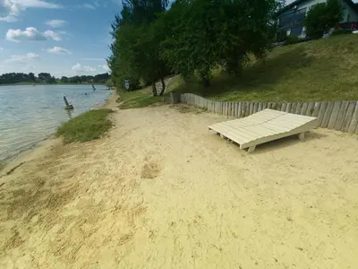 a bench sitting on a sandy beach next to the water at Gilužio Rivjera in Vilnius