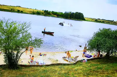 a group of people on a beach with a boat in the water at Gilužio Rivjera in Vilnius