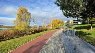 a winding path in a park with trees and a building at Gilužio Rivjera in Vilnius