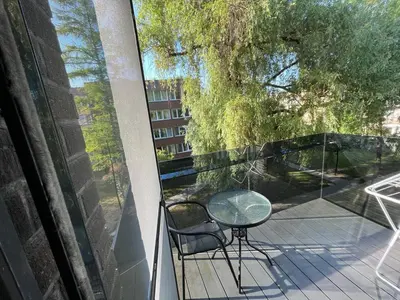 a glass table and a chair on a balcony at Birstonas Holidays Apartment in Birštonas
