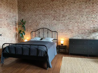 a bedroom with a black bed and a brick wall at Traukinių namai #1 in Švenčionėliai