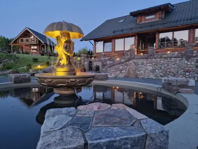 a fountain in the middle of a pond in front of a house at Viesu vila Trakai ,su ežero pakrante in Meiluškės