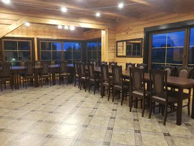 a dining room with tables and chairs and windows at Viesu vila Trakai ,su ežero pakrante in Meiluškės