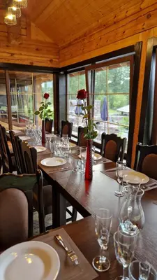 a dining room with a long table with wine glasses at Viesu vila Trakai ,su ežero pakrante in Meiluškės