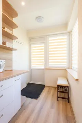 a kitchen with white cabinets and two windows at Senamiesčio apartamentai in Druskininkai