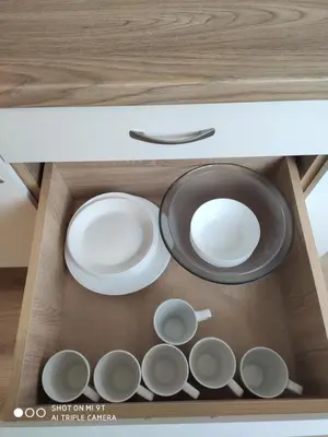 a wooden drawer with plates and dishes in it at Senamiesčio apartamentai in Druskininkai