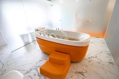 an orange bath tub sitting in a bathroom at Mineral SPA Draugystė in Druskininkai