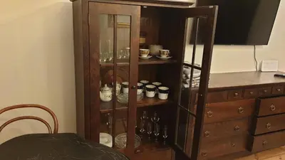 a wooden cabinet with bottles and dishes in it at kauno street home in Vilnius