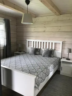 a bedroom with a white bed and wooden walls at Atostogų namelis Laukys in Druskininkai