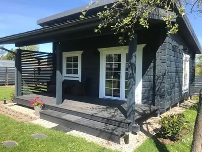 a small black house with a porch and a window at Atostogų namelis Laukys in Druskininkai