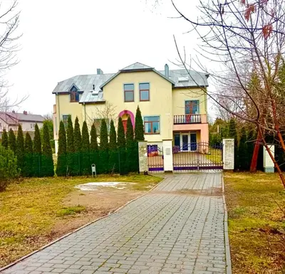 a large house with a fence and a brick driveway at Wonderful 8 Bedroom Home near Vilnius in Didžioji Reišė