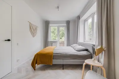 a bedroom with a bed and two windows and a chair at Central Apartment in Architectural Street in Kaunas