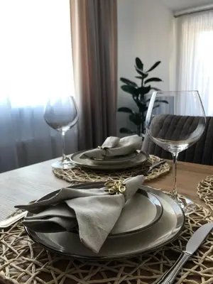 a dining room table with plates and glasses on it at Saulės Tako apartamentai in Druskininkai