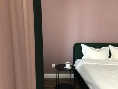 a bedroom with a bed and a table with a cup on it at Saulės Tako apartamentai in Druskininkai