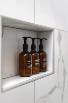 three bottles of soap sitting on a shelf in a bathroom at Saulės Tako apartamentai in Druskininkai