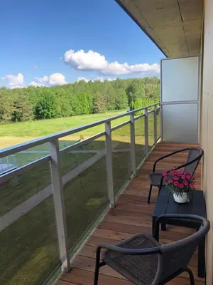 a balcony with two chairs and a table with flowers at Saulės Tako apartamentai in Druskininkai