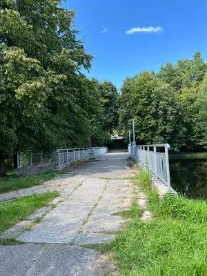 a bridge over a body of water with trees at Saulės Tako apartamentai in Druskininkai